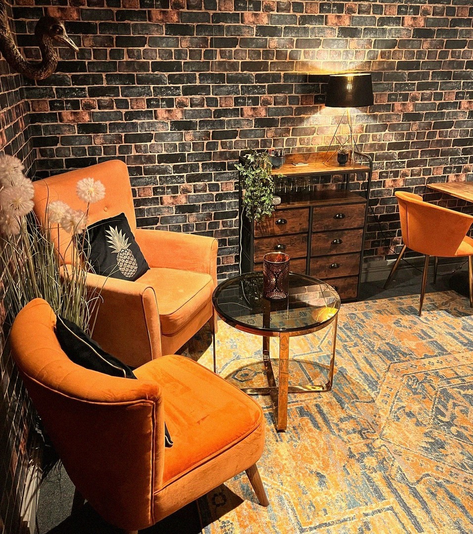 Cozy interior of Mamma J's with orange velvet chairs, exposed brick wall and warm lighting