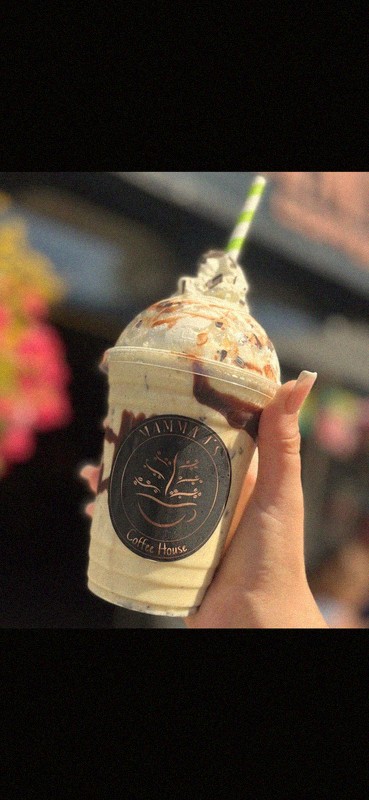 Mamma J's branded iced frappe with whipped cream and chocolate drizzle, held in hand